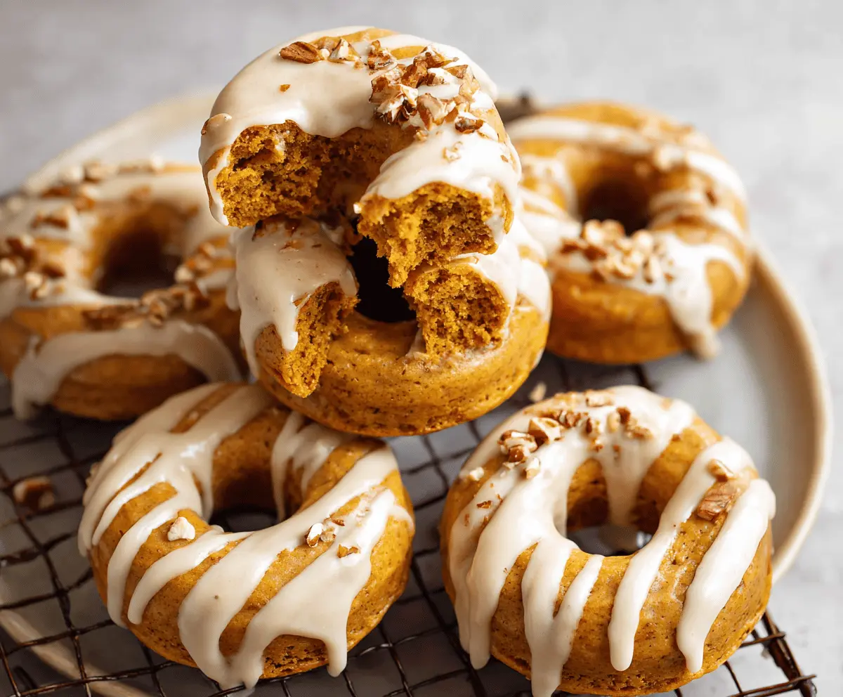 Freshly baked pumpkin donuts with cinnamon glaze on a rustic plate, perfect for fall treats.