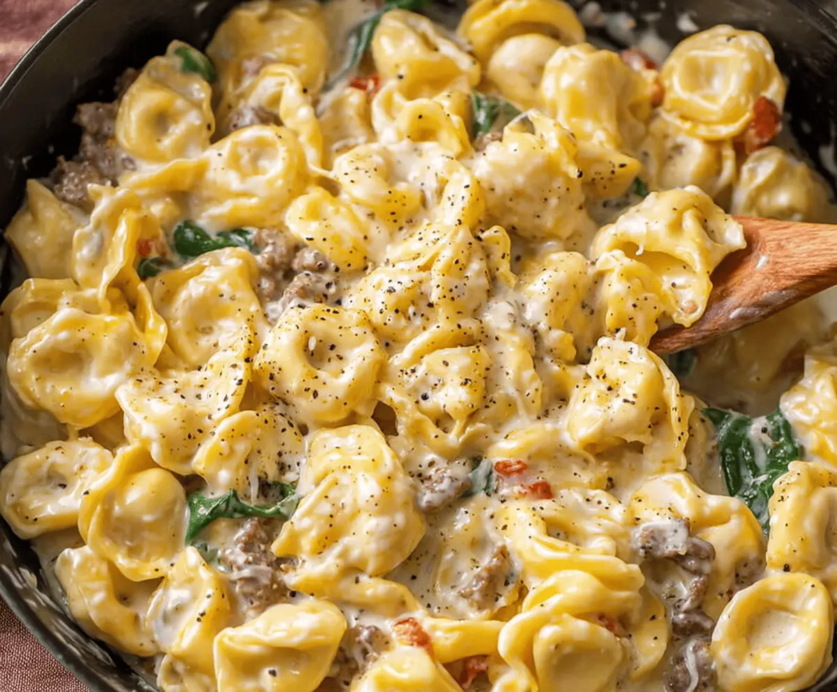 Creamy garlic butter beef and spinach tortellini served on a plate with fresh herbs and grated Parmesan cheese.