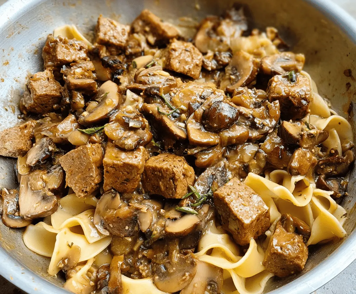 Creamy mushroom and seitan stroganoff served in a bowl with fresh herbs, perfect for a hearty vegan meal.