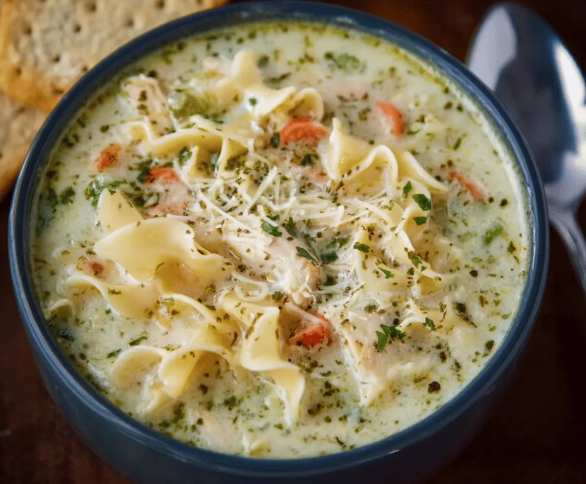 Creamy white chicken lasagna soup in a bowl with melted cheese, tender chicken, spinach, and pasta, topped with fresh herbs—perfect comfort food recipe.