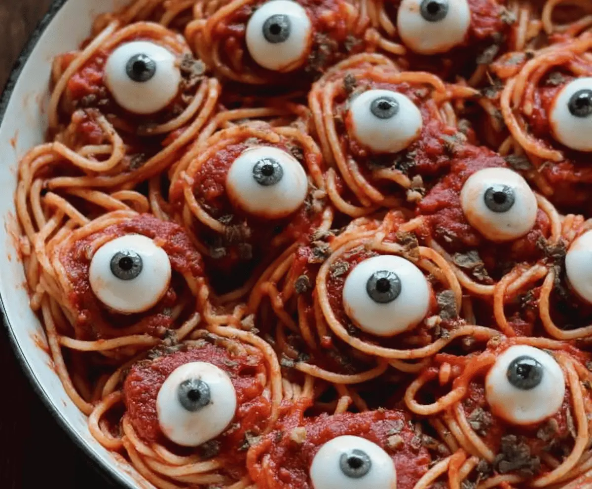 Spooky Bloody Spaghetti with Mozzarella Eyeballs Halloween Pasta dish featuring red sauce, mozzarella balls with olives, perfect for Halloween-themed meals