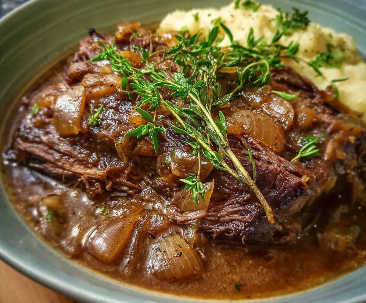 Delicious French onion pot roast with caramelized onions and tender beef served in a rustic dish.