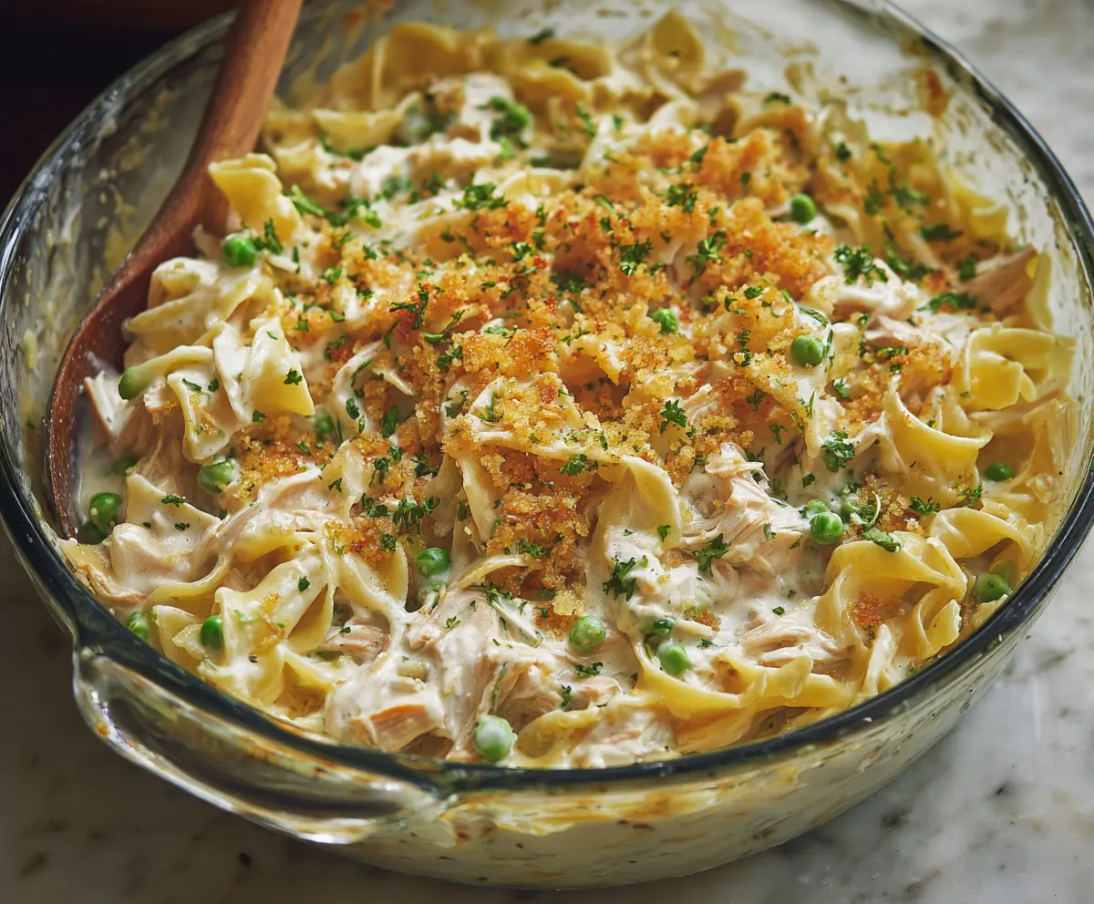 Delicious creamy tuna noodle casserole topped with cheese and fresh herbs on a dinner plate.