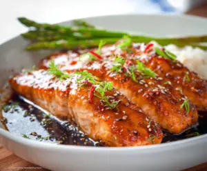 Delicious glazed teriyaki salmon served with fresh vegetables on a plate.