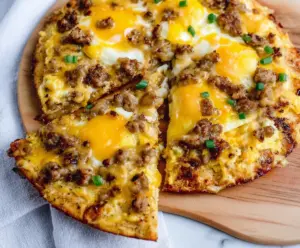 High protein sausage and egg breakfast pizza on a plate, topped with fresh herbs