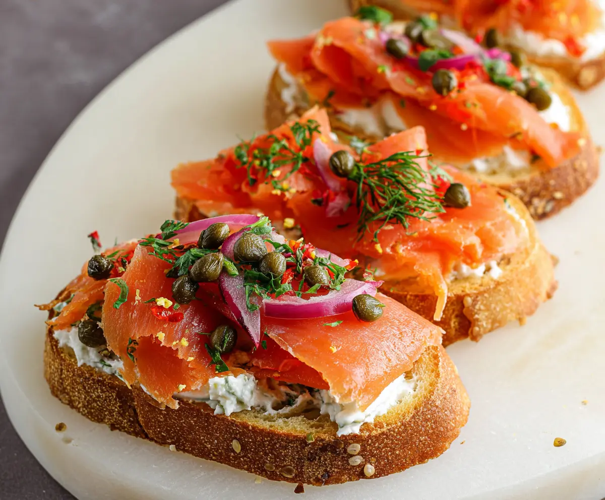 Delicious smoked salmon bruschetta on crusty bread garnished with herbs and lemon for a savory appetizer.