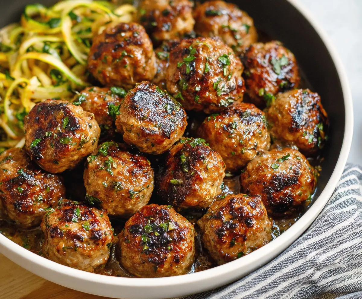 Delicious Keto Garlic Butter Meatballs served on a plate with fresh herbs.