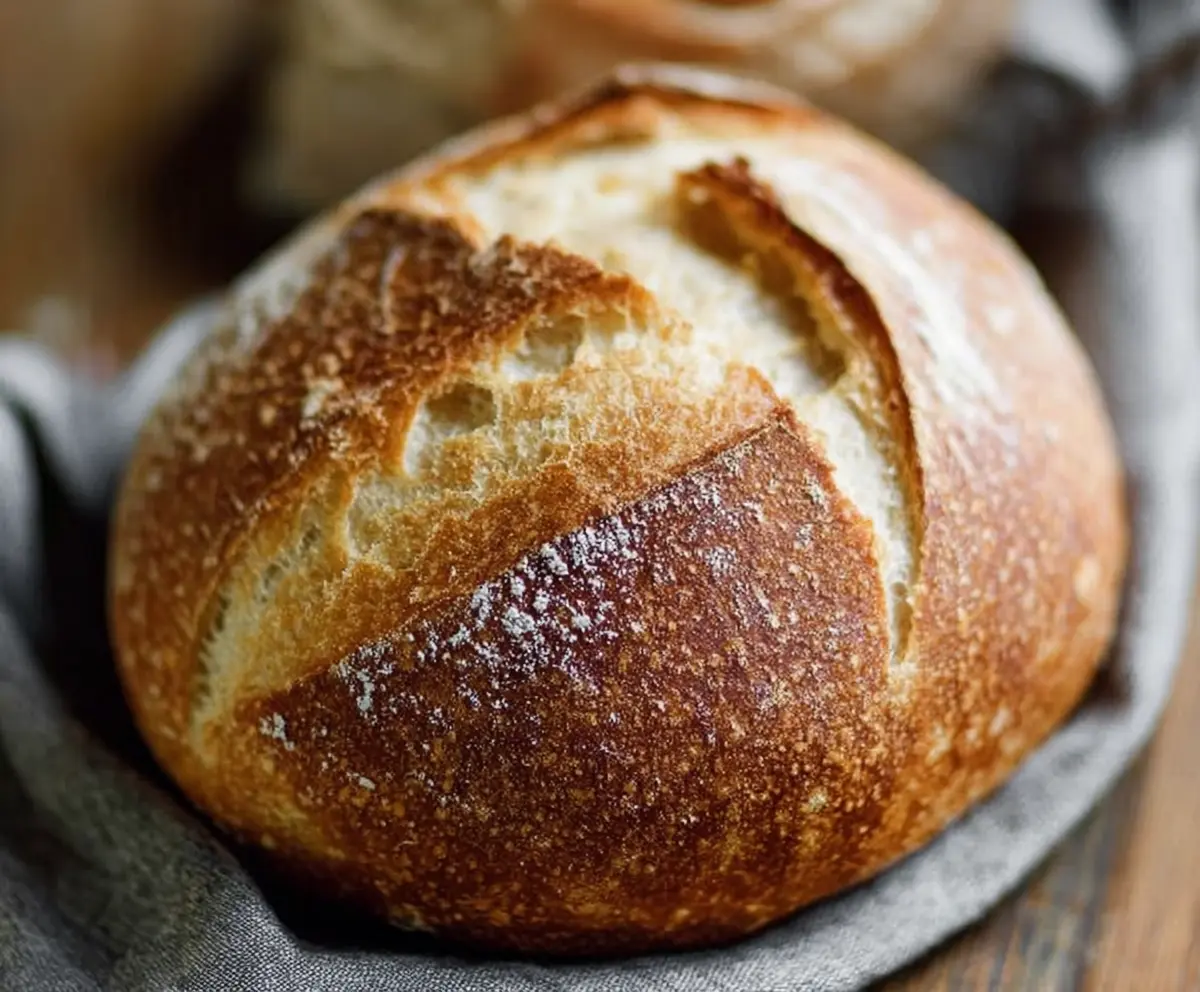 Freshly baked sourdough bread with a golden crust on a rustic breadboard.