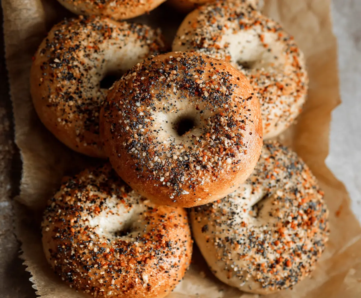 Delicious homemade sourdough bagels on a wooden board with sesame seeds.